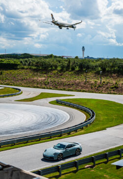 A Porsche races around the Porsche Experience Center in Atlanta as a Delta airplane comes in for a landing